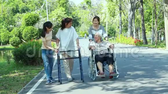 快乐的亚洲家庭年长的妇女残疾的祖母带着步行机和轮椅女儿十几岁的孙女正在享受散步视频的预览图