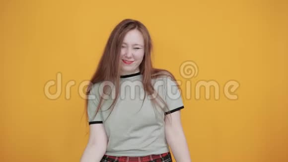 橙色墙上的年轻女子笑着做岩石符号视频的预览图