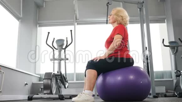 快乐的资深运动员在健身房练习健身球运动型养老金领取者的概念坐着的老太太视频的预览图