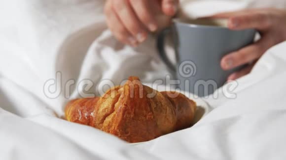 女人在床上用咖啡吃羊角面包的手视频的预览图