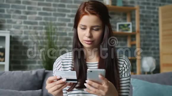 快乐的女士在网上购物用智能手机和银行卡支付感觉很快乐视频的预览图