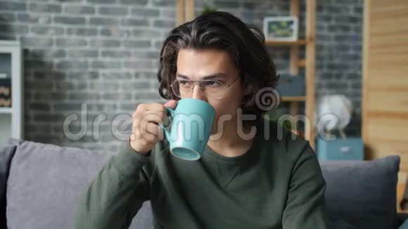 戴眼镜的帅哥在家喝杯酒的慢动作视频的预览图