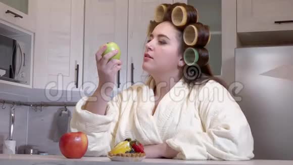 另外一个穿着浴袍头上有卷发的大女孩看着苹果不想吃视频的预览图