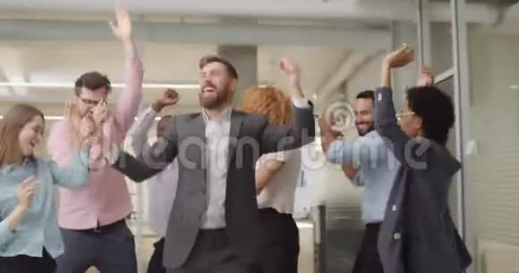 年轻的多样化的商业工作者在完成工作日后心情愉快地在一起玩群经理跳舞视频的预览图