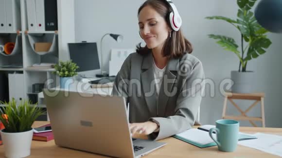 风趣的女士戴着耳机听音乐跳舞用笔记本电脑玩得开心视频的预览图