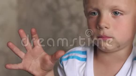 一个肮脏的小男孩的脸的特写镜头那孩子在街上玩得脏兮兮的视频的预览图