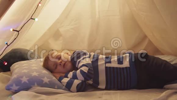 小男孩睡在孩子们家里帐篷里快乐的白种人小孩在游戏室视频的预览图