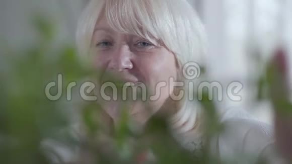 微笑的高加索人老太太向家花喷水的特写镜头身后幸福退休人员的画像视频的预览图