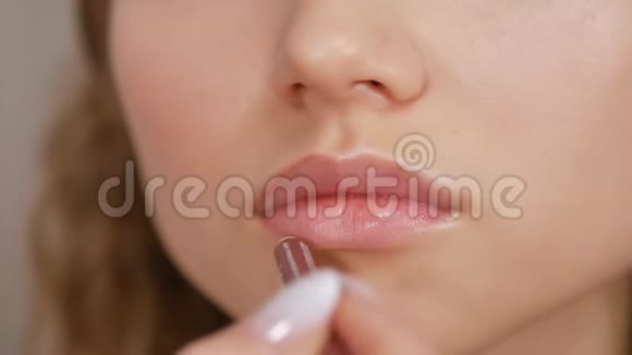 一个年轻女孩的脸在女孩的嘴唇上涂颜料视频的预览图