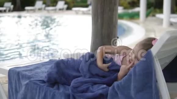 一个小女孩躺在孩子们游泳池旁的一个茶座里视频的预览图