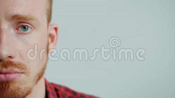 灰蓝色背景上半张脸的长着胡子的年轻人的肖像视频的预览图