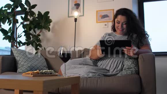有平板电脑的女人在家喝红酒视频的预览图