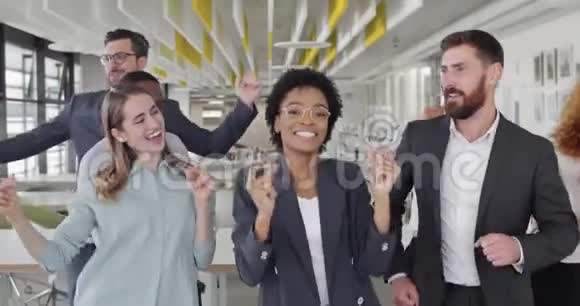 喜出望外的多种族同事为公司的胜利和在一起的乐趣而欢呼年轻的办公室职员跳舞视频的预览图