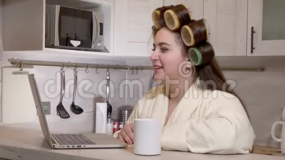 超大号的女孩穿着浴衣头上戴着卷发器通过视频通话视频的预览图