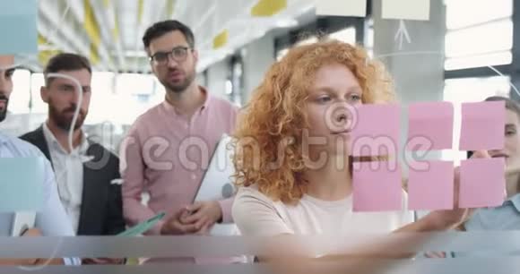 关闭女办公室工作人员使用玻璃板并提出她的问题解决同事不同的同事视频的预览图