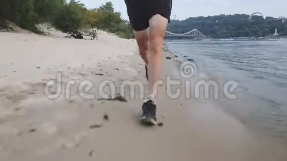 训练有素的肌肉男腿在河滩上跑步积极运动的人在河边奔跑的正面景色强壮有力的腿部慢跑视频的预览图