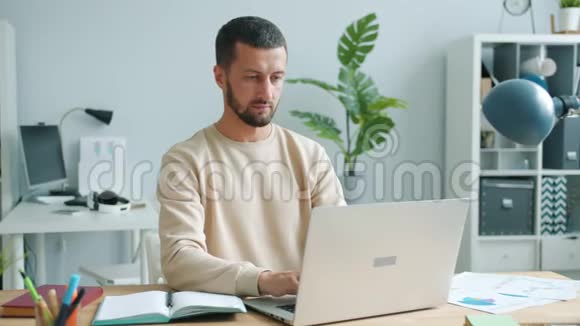 工作累了的人拿着笔记本电脑在办公室工作摸着眼睛和脸感到精疲力竭视频的预览图