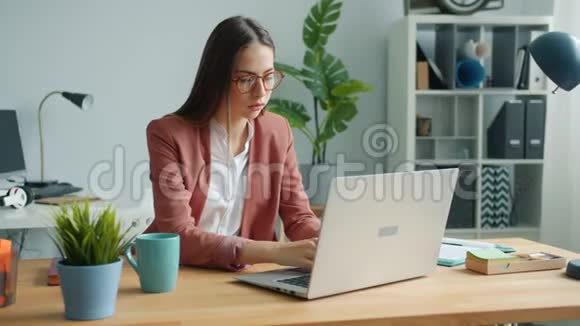 美丽的女人用电脑然后摘下眼镜触摸办公室的眼睛视频的预览图