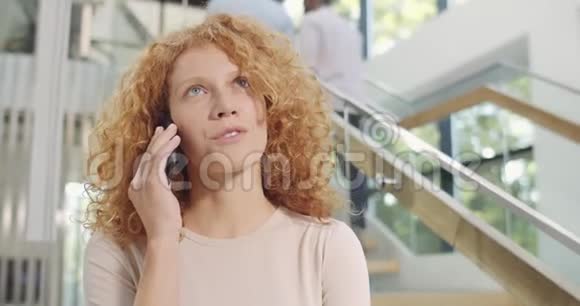 关闭有吸引力的女上班族站在手机上交流年轻的卷发女商人视频的预览图