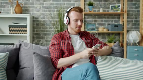 耳机听音乐和使用智能手机的快乐男人的慢动作视频的预览图