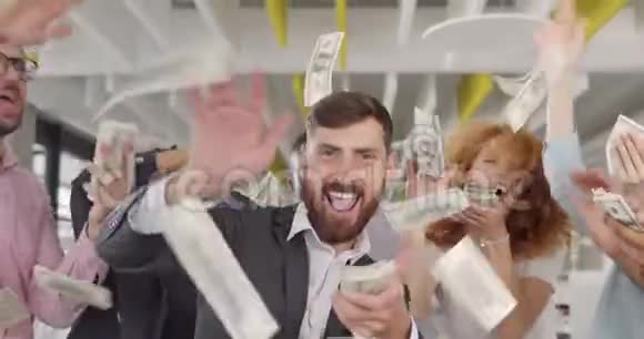 英俊的男局长散落钞票在他的同事圈里跳舞商务人员为大钱而高兴视频的预览图