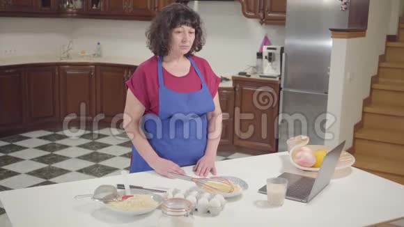 布鲁内特白种人成熟的女人在家里的厨房做饭高级退休人员在线检查配方和面团混合视频的预览图