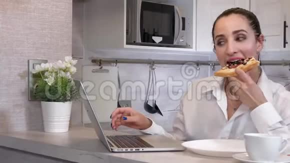 年轻的女商人在厨房里吃一块披萨视频的预览图