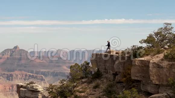 徒步女徒步走到大峡谷悬崖边缘举起双手跳跃视频的预览图
