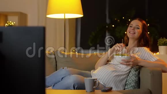 快乐微笑的孕妇在家看电视视频的预览图