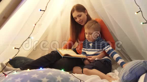小男孩在家里孩子们的帐篷里玩妈妈在读童话书快乐的白种人小孩在游戏室视频的预览图