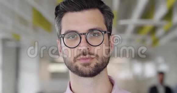 一个30多岁的留着胡子的白种人盯着镜头眨眼睛有着严肃面孔的帅哥画像视频的预览图