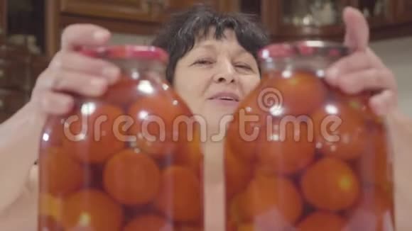 快乐的白种人女性退休者的特写镜头将装有罐装番茄的瓶子分开伸出大拇指眨眨眼视频的预览图