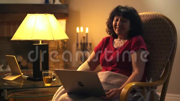 积极的白人女人坐在摇椅上拿着笔记本电脑大声笑出来快乐的女性退休金领取者视频的预览图