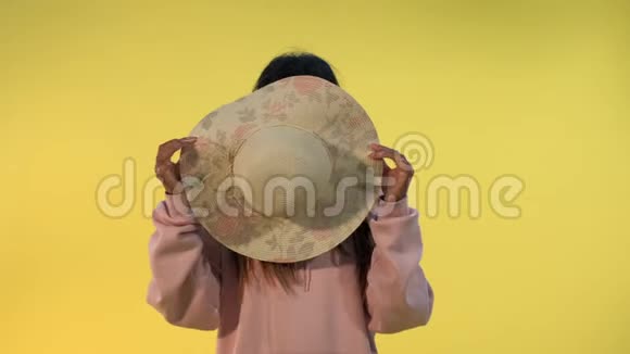 微笑的非洲女人躲在黄色背景的帽子后面视频的预览图