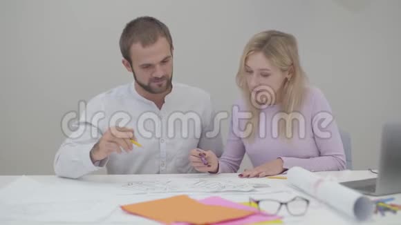 两个白人专业设计师在办公室里看蓝图年轻漂亮的女人和英俊的男人视频的预览图