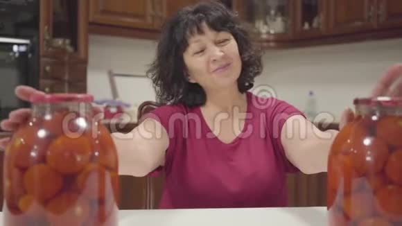 高加索成熟女人欣赏她的罐头前景是装着罐装番茄酱的瓶子快乐退休者视频的预览图