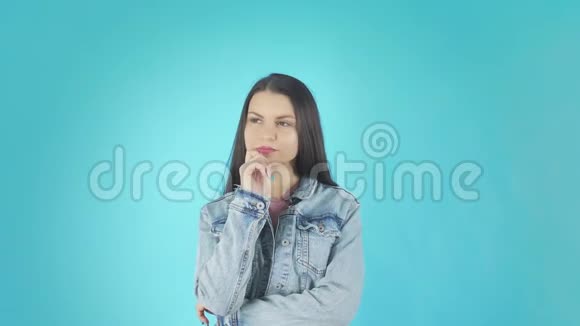 年轻的忧心忡忡的女孩站在那里祈祷好运在蓝色的背景下孤立无援视频的预览图