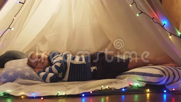 小男孩睡在家里的儿童帐篷里快乐的白种人小孩在游戏室视频的预览图