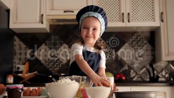 一个小女孩把面团准备成纸杯蛋糕她把葡萄干倒在面团里视频的预览图