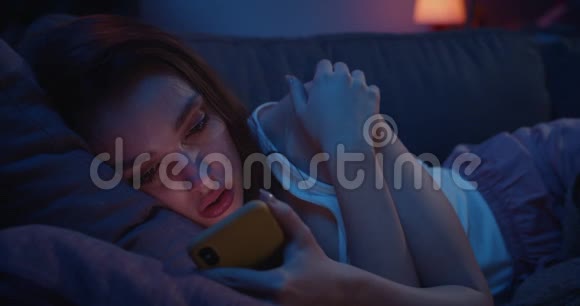 合上躺在沙发上盯着智能手机屏幕的不幸年轻女子千禧一代女性感到沮丧视频的预览图