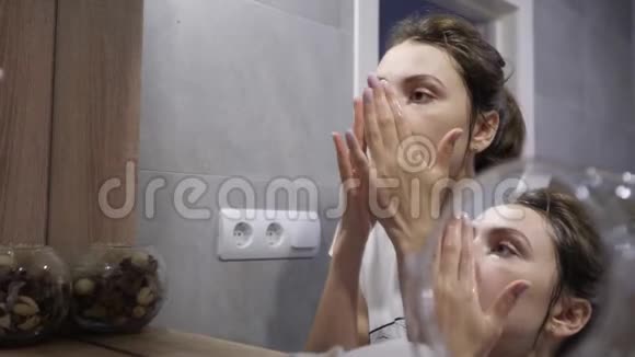 幸福的年轻女人用天然化妆品洁面后用白色毛巾擦拭她的脸反思视频的预览图