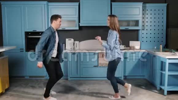 家庭舞会快乐年轻夫妇在家厨房做饭时跳舞很有趣摇滚舞蹈动作视频的预览图
