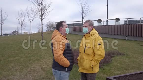 两个戴着口罩的男人在户外谈话视频的预览图