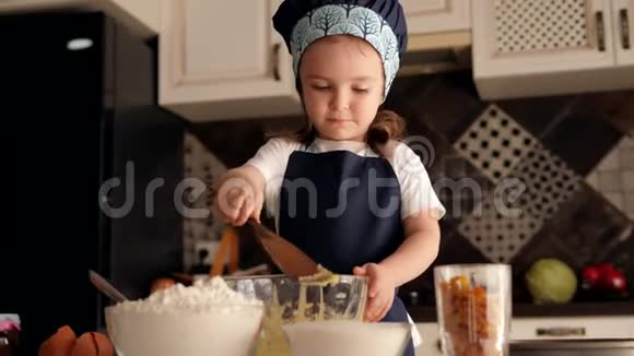 一个三岁的小女孩戴着帽子和围裙为饼干准备面团视频的预览图