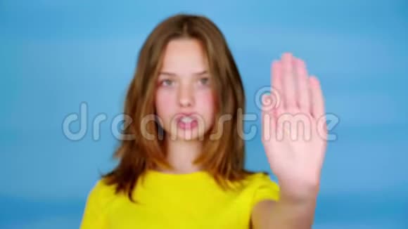 穿黄色T恤的少女看着镜头伸出手在前面说停视频的预览图