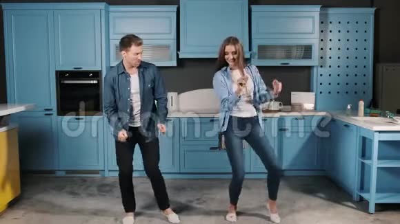 家庭舞会快乐年轻夫妇在家厨房做饭时跳舞很有趣双舞动作视频的预览图