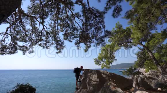 旅行者爬过海边的一块岩石视频的预览图