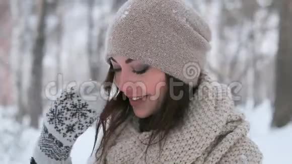一个蓝眼睛的漂亮女孩在一个冬天的公园里摆姿势微笑着用一只手穿过她的头发视频的预览图