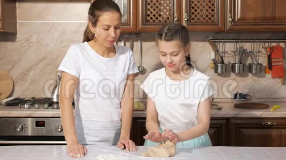 妈妈正在教她十几岁的女儿如何在家里的厨房里做面团视频的预览图