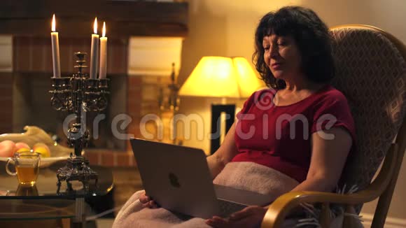 漂亮的白种人成熟的女人在看电影或电视剧并吹灭蜡烛后关闭笔记本电脑快乐的女人视频的预览图